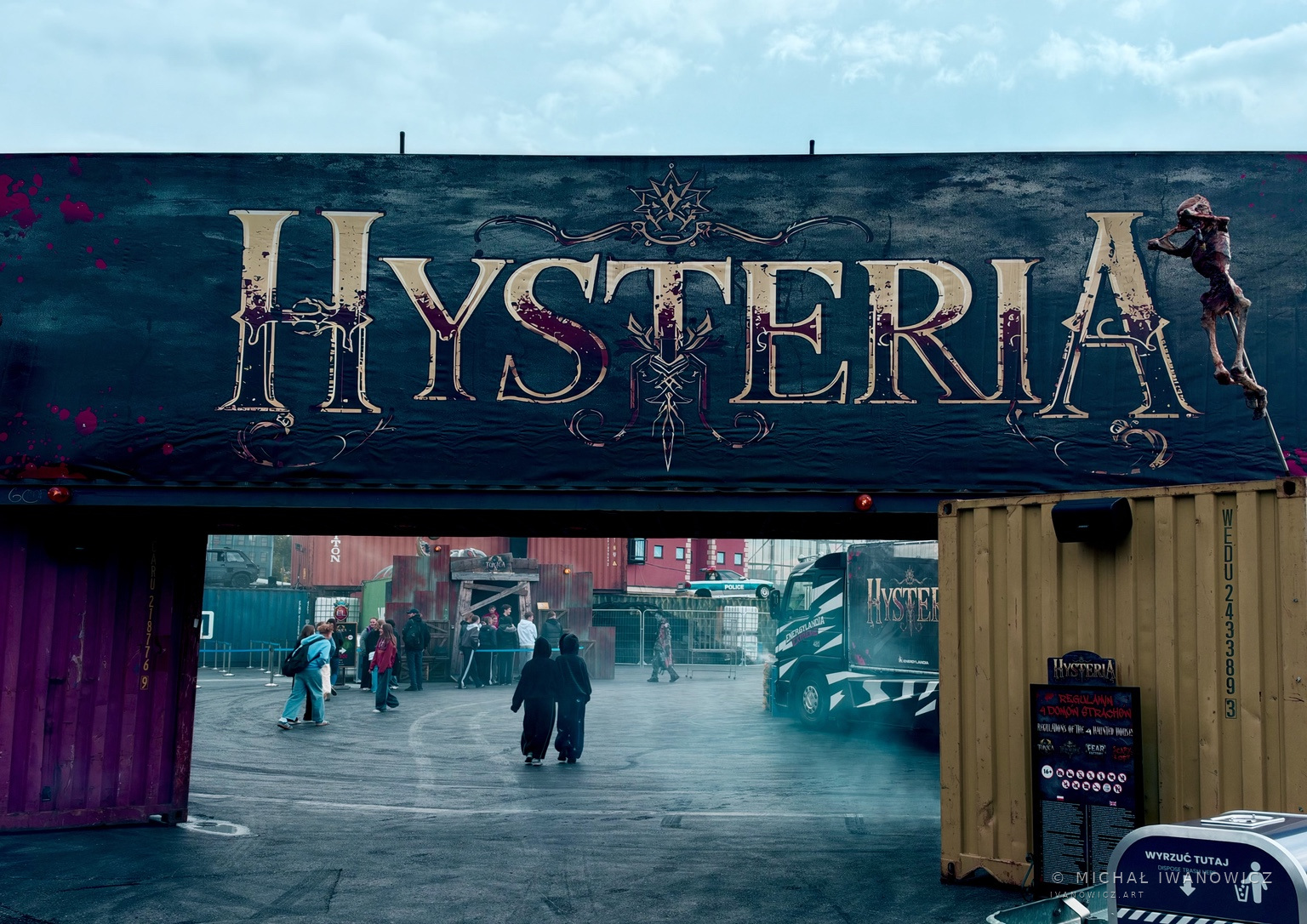 Wejście z napisem Hysteria i przechodnie we mgle